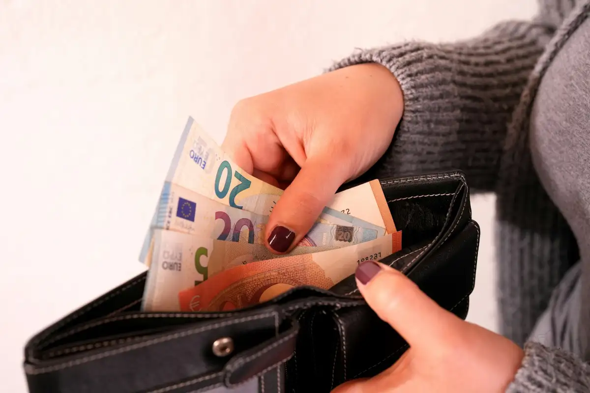 Person nimmt Geldscheine aus dem Portemonnaie, um eine Rate zu bezahlen