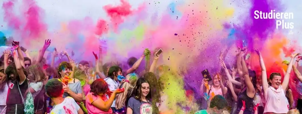 Feiernde Studierende mit bunten Farbpulvern bei einem Holi-Festival während der Studienzeit