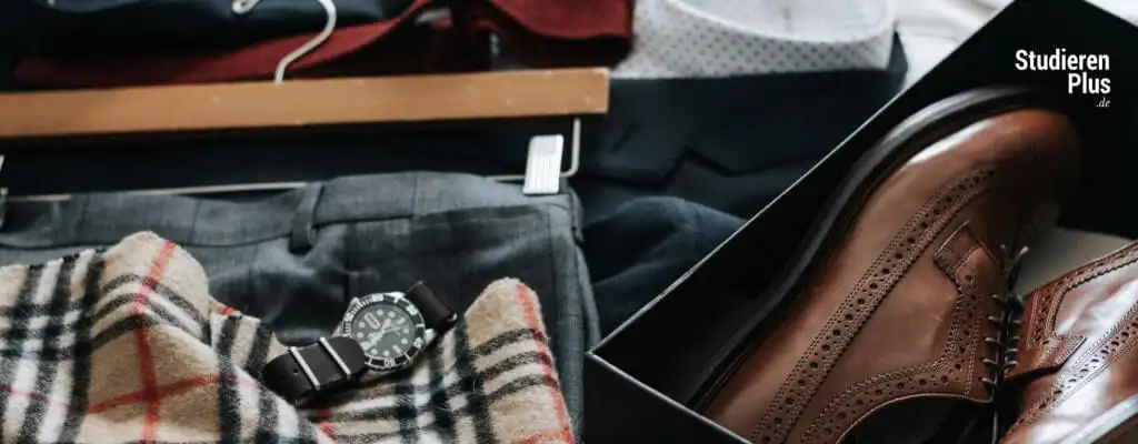 Zurechtgelegtes Outfit mit Anzug, Uhr und braunen Lederschuhen zur Vorbereitung aufs Bewerbungsgespräch
