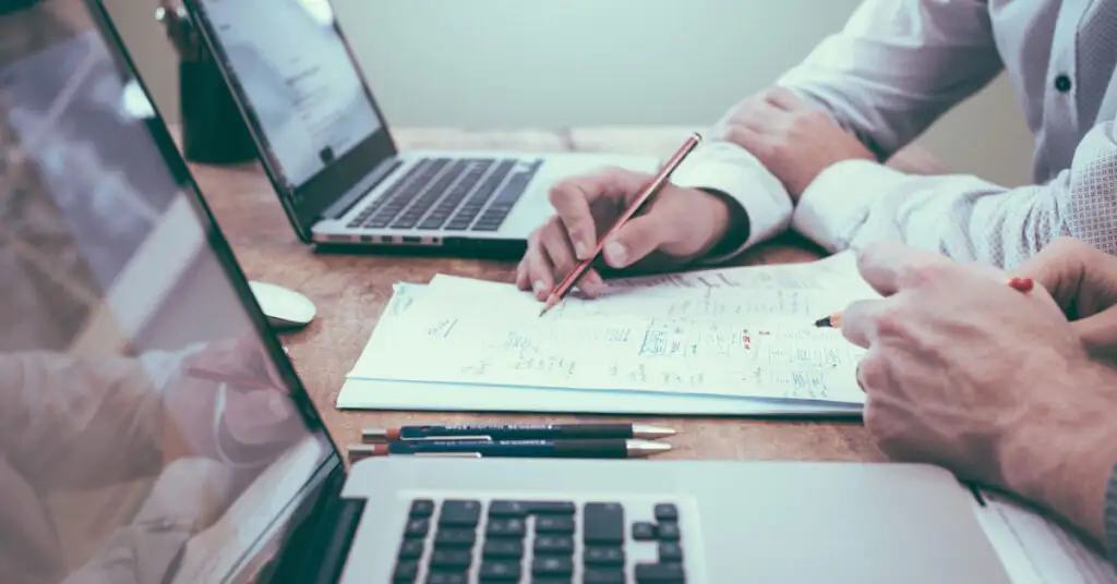 Zwei Personen arbeiten mit Laptops und Notizen gemeinsam an einem Online-Kurs